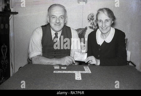 1950, ältere Paare an einem Tisch spielen 'Kan-U-Go", eine alte Kreuzworträtsel Kartenspiel, England, Großbritannien sitzen. Für 2 bis 7 Spieler, das Spiel stammt aus den 1930er Jahren und hat kleine Karten mit Buchstaben und Werte und einfache Regeln für die Wiedergabe und Riefenbildung, Stockfoto