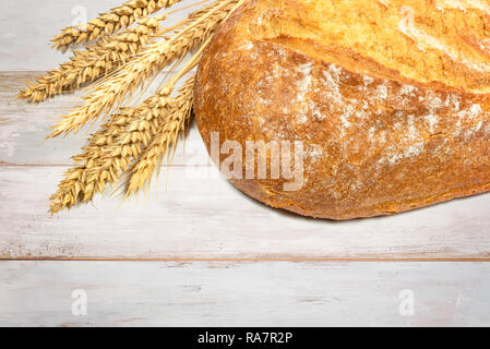 Frisches Brot mit Weizen Körner auf einem hölzernen vintage Tabelle in Nahaufnahme. Stockfoto