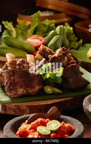 Iga Penyet. Javanisch gebraten - dann - zertrümmerte Rindfleisch Rippen mit roter Chili Paste und frischem Gemüse serviert. Stockfoto