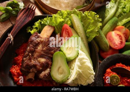 Iga Penyet. Javanisch gebraten - dann - zertrümmerte Rindfleisch Rippen mit roter Chili Paste und frischem Gemüse serviert. Stockfoto