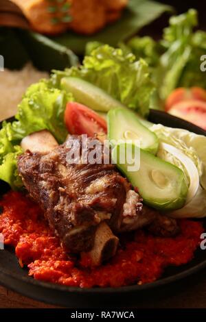 Iga Penyet. Javanisch gebraten - dann - zertrümmerte Rindfleisch Rippen mit roter Chili Paste und frischem Gemüse serviert. Stockfoto