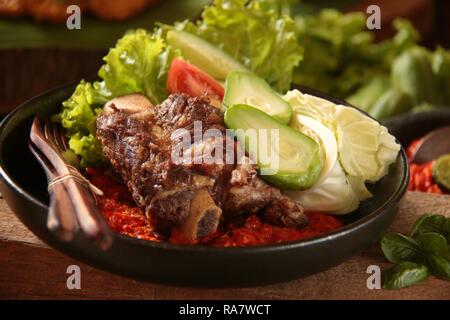 Iga Penyet. Javanisch gebraten - dann - zertrümmerte Rindfleisch Rippen mit roter Chili Paste und frischem Gemüse serviert. Stockfoto