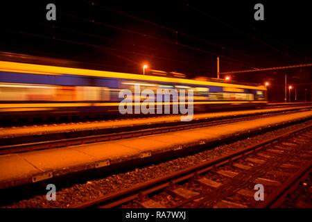 Personenzug auf Bahngleise bei Nacht verschwommene Bewegung Stockfoto