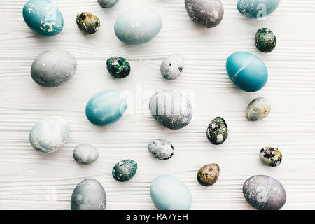 Stilvolle Ostereier auf weißem Hintergrund Holz, flach. Moderne Ostereier mit natürlichen Farbstoff in blauem und grauem Marmor Farbe lackiert. Frohe Ostern Patt Stockfoto