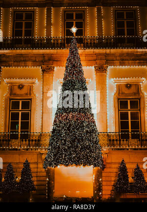 Beleuchteter Christbaum gegen Gebäude im portugiesischen Stil, in Lissabon, Portugal. Stockfoto