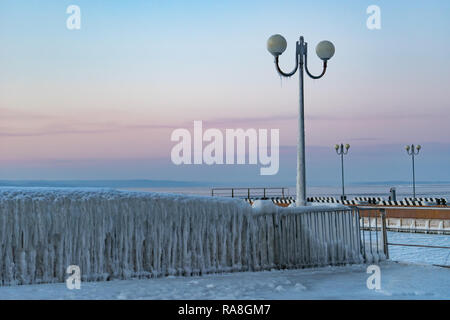 Winterlandschaft mit eisiger Zaun auf dem Hintergrund der Himmel und das Meer. Stockfoto