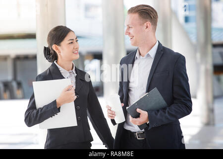 Business sprechen im Freien zwischen asiatischen Frau und weißen Kerl Stockfoto