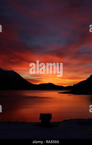Atemberaubenden Sonnenaufgang über See und Berge mit Hütte Silhouette Stockfoto