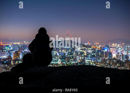 Junger Mann Reisender sitzen auf den Felsen in der Nacht suchen Stadt Seoul, Südkorea Stockfoto