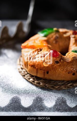 Nahaufnahme eines roscon de Reyes, drei Könige Kuchen auf epiphanie Tag gegessen Spanisch, auf einem grauen rustikalen Tisch Stockfoto