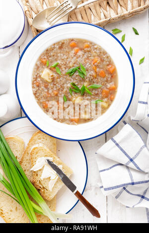 Buchweizen Suppe mit Karotte und Kartoffel auf weißen Holzmöbeln rustikal Tisch. Gesunde vegetarische Kost, Ansicht von oben Stockfoto