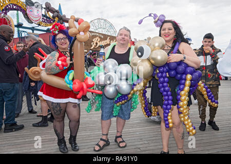 Drei Leute in Kostümen mit Ballons auf dem Boardwalk Coney Island vor der Tag der jährlichen Polar Bear Club Das neue Jahr Schwimmen in Coney Island, New York. Stockfoto