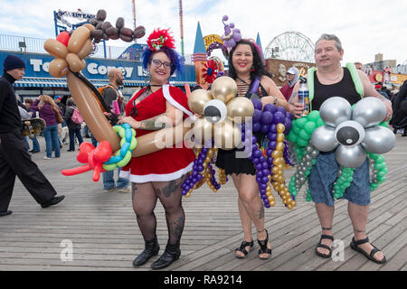 Drei Leute in Kostümen mit Ballons auf dem Boardwalk Coney Island vor der Tag der jährlichen Polar Bear Club Das neue Jahr Schwimmen in Coney Island, New York. Stockfoto