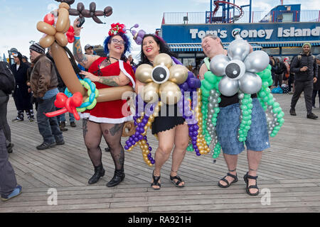 Drei Leute in Kostümen mit Ballons auf dem Boardwalk Coney Island vor der Tag der jährlichen Polar Bear Club Das neue Jahr Schwimmen in Coney Island, New York. Stockfoto