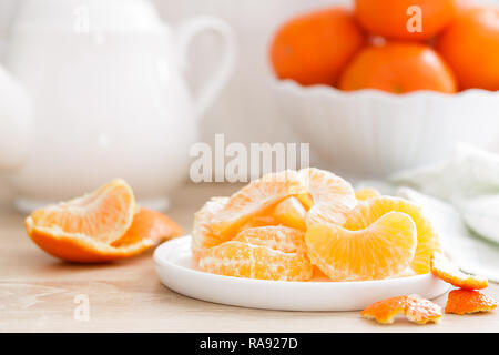 Mandarinen. Süß lecker geschälte Mandarinen auf Platte auf weiße Küche Hintergrund Nahaufnahme. Gesunde und Leckere vegane, vegetarische Kost. Stockfoto