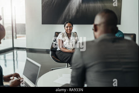 Sicher schöne afrikanische bsuiness Frau im Gespräch mit Kolleginnen und Kollegen während einer Konferenz Stockfoto