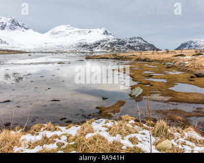 Schmelzender Schnee und Eis bei Ebbe in der Bucht von Flakstadpollen Flakstadoya, Lofoten, Nordland, Norwegen Stockfoto