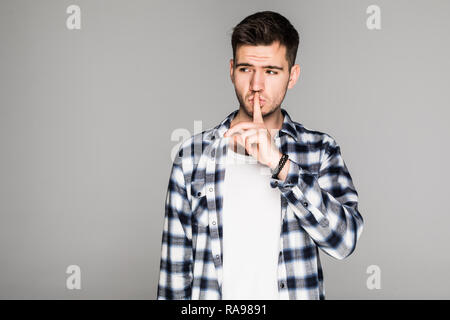 Porträt von Ernst modisch Männlich gekleidet trendy im blauen Hemd, hält die Zeigefinger auf die Lippen, sodass shh Geste für geheime oder ruhig sein. Isolierte Schuß Stockfoto