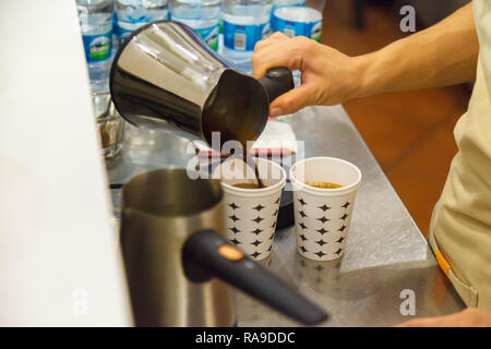 Das Mädchen gießt frisch zubereitete warme, duftende Türkischen Kaffee in einem Glas für den Client. Close-up Stockfoto