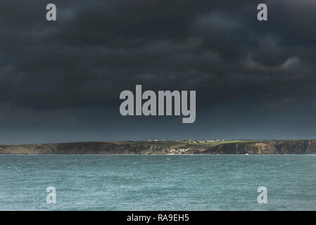 Dunkle stürmische brütende Himmel mit Sonnenlicht auf Watergate an der Küste von North Cornwall. Stockfoto