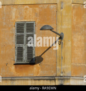 NIZZA, FRANKREICH - 25. MAI 2018: Alte Lampe und Fensterläden auf gelbem Wohngebäude als Hintergrund Stockfoto