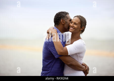Reifer Mann küsste seine Frau am Strand. Stockfoto