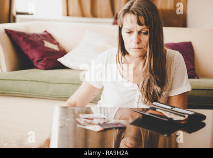 Reife Frau ist aufgebracht, an die Kreditkarten aus der Brieftasche zu suchen Stockfoto