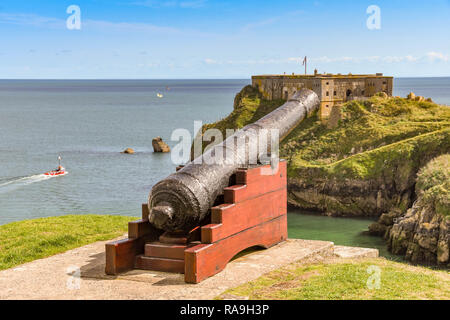 TENBY, Pembrokeshire, Wales - AUGUST 2018: alte Kanone mit Blick auf das Schloss und Strand St Catherine's Insel in Tenby, West Wales. Stockfoto
