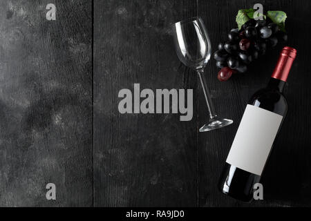 Rotwein Flasche mit Glas Wein und Trauben auf dunklen Holztisch flach von oben mit Kopie Raum Stockfoto
