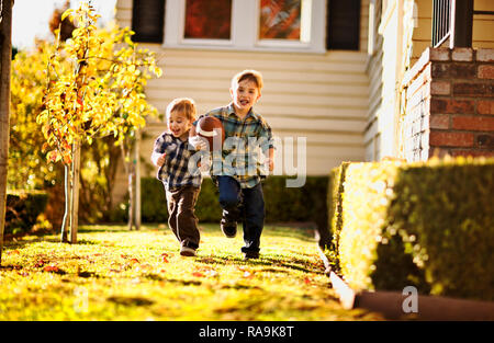 Laufen Junge spielt Fußball im Hinterhof mit seinem Bruder. Stockfoto
