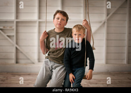 Porträt von zwei Jungen auf einer Schaukel sitzend. Stockfoto