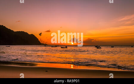 Sonnenuntergang über dem kleinen, abgelegenen Dorf von Castara auf der wunderschönen Insel Tobago in der Karibik mit Seevögeln und Fischerbooten. Landschaft Stockfoto