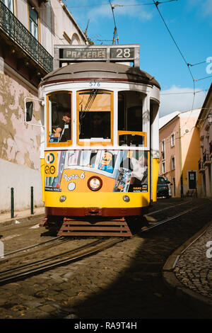 Lissabon, Portugal - Januar 01, 2018: Iconic gelb Straßenbahnlinie 28 in Lissabon, Portugal. Der Lissaboner Straßenbahn Fahren auf schmalen Straße an einem sonnigen Tag. Stockfoto