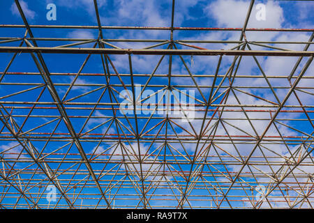 Urban abstrakte Textur Hintergrund. Sicht in blauer Himmel durch alte rostige Geometrische diagonal Metall Konstruktionen von verlassenen Gebäude Stockfoto