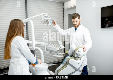 Zahnarzt mit Frau assistant Vorbereitung Arbeitsplatz für das Verfahren in der Zahnarztpraxis Stockfoto