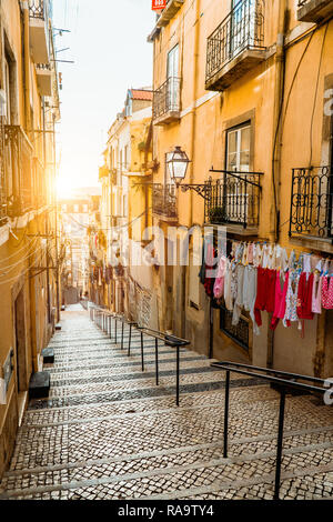 Treppe in der Straße mit Kopfsteinpflaster in Lissabon. Hängende Wäsche in typischen schmalen Straße. Sonnenuntergang in der Altstadt von Lissabon, Eindrücke von der Stadt Stockfoto