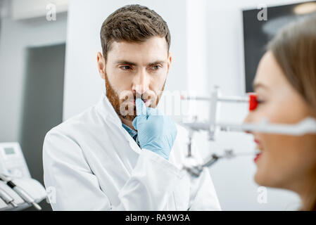 Porträt einer durchdachten Zahnarzt bei der Arbeit mit jungen Frau Patient in der Zahnarztpraxis Stockfoto