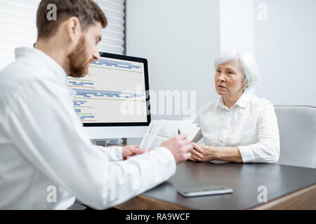 Ältere Frau Patienten während der ärztlichen Beratung mit männlichen Arzt im Büro Stockfoto