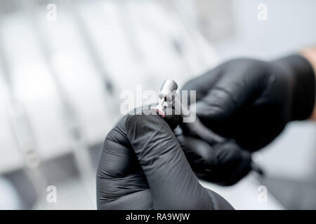 Nahaufnahme einer zahnmedizinischen Bohrer mit Düse in die Hände in Schwarz medizinische Handschuhe Stockfoto