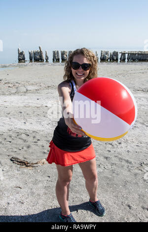 Ein erwachsenes Weibchen hält einen Beach Ball in der Luft an den verlassenen Bombay Strand am Salton Sea in Südkalifornien. Stockfoto