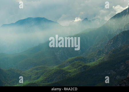 Erstaunlich schöne Berglandschaft mit hübschen Wolken und weichen Sonnenstrahlen fallen auf der Erde durch dicke Wolken. Natur Hintergrund. Horizontale Stockfoto