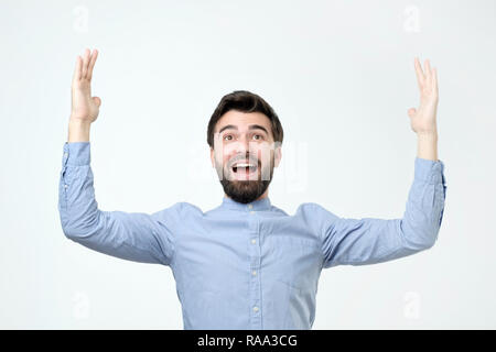 Glückliche junge bärtige Mann prahlen die Größe von etwas Stockfoto