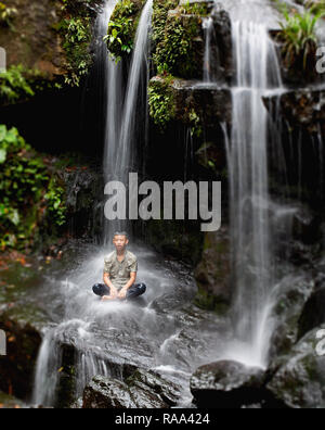 Junge vietnamesische Jungen unter dem Wasser sitzen an thac Gio Wasserfall, Botanischen Gärten im Phong Nha, Vietnam, Asien Stockfoto