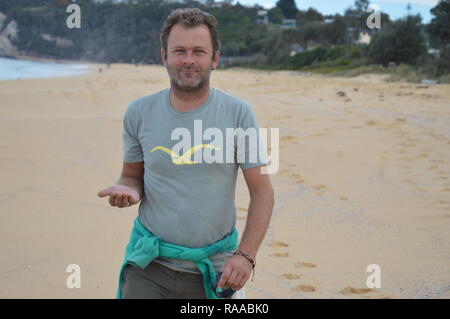 Mann, der an einem Strand mit Palmen angehoben Stockfoto