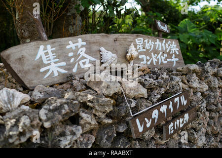 Holz- Schild an der Straße mit traditionellen Steinmauern an der tropischen Insel Taktomi in Japan Stockfoto