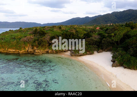 Luftaufnahme über einzigartige tropische Insel mit Berge, einsame weisse Sandstrände und Coral Reef, bei Sonnenuntergang, von Drohne, Ishigaki, Japan Stockfoto