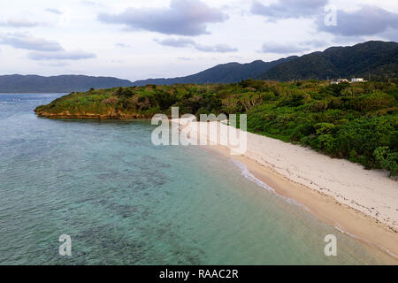 Luftaufnahme über einzigartige tropische Insel mit Berge, einsame weisse Sandstrände und Coral Reef, bei Sonnenuntergang, von Drohne, Ishigaki, Japan Stockfoto