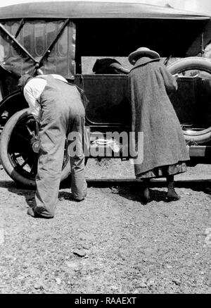 Ma und Pa arbeiten Seite an Seite Reifenwechsel auf ihre Periode Automobil, Ca. 1925. Stockfoto