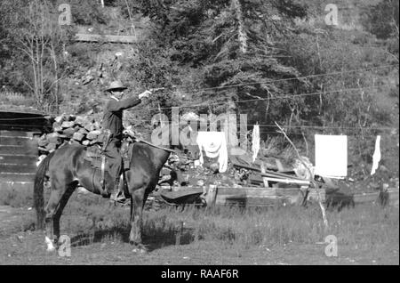 Ein Mann auf einem Pferd Praktiken mit seiner Pistole, Ca. 1920. Stockfoto