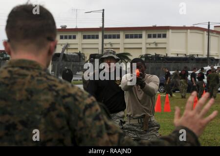 Us-Flieger Staff Sgt. Lionel Rhone, Militär, Polizei, seine Pistole auf einer simulierten Aggressor während der Durchführung einer Oleoresin Capsaicin (OC) Exposition Kurs während einer Non-Lethal Waffen Instructor Kurs an Bord Camp Hansen, Okinawa, Japan, Jan. 13, 2017. Der Kurs vermittelt Personal die korrekten Techniken bei der Durchführung von Taser Ausbildung, OC-Exposition und riot control Team Taktik. Stockfoto